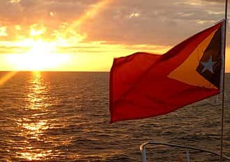 Flying flag of East Timor at sunset